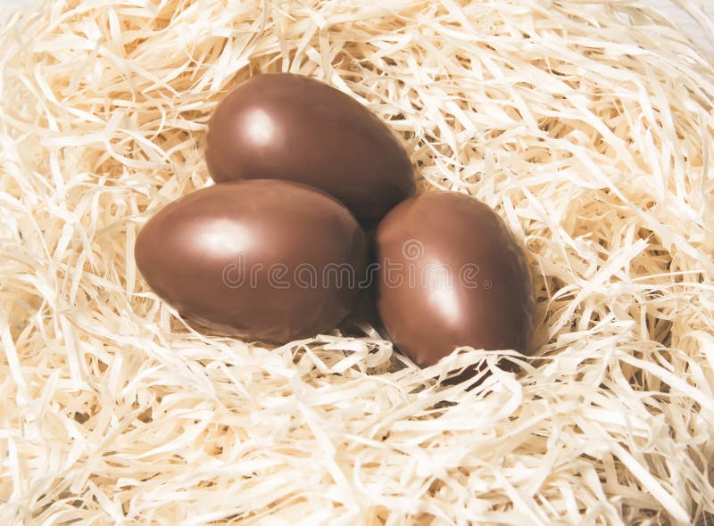 Easter. Chocolate eggs lie in a nest on a wooden white table stock images Easter. Chocolate eggs lie in a nest on a wooden white table stock images