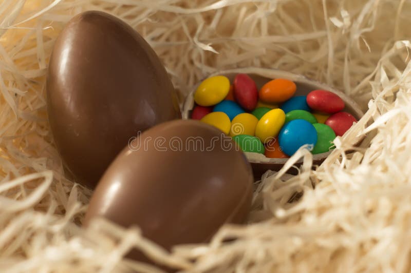 Easter. Chocolate eggs with multicolored candies lie in a nest on a wooden white table royalty free stock images Easter. Chocolate eggs with multicolored candies lie in a nest on a wooden white table royalty free stock images