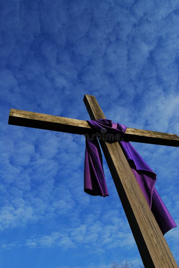 Viejo de madera cruz contra el cielo una pieza de púrpura tela colgante eso.