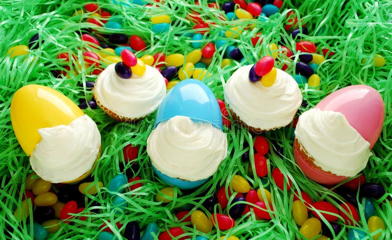 Cupcakes displayed in Easter eggs. Set on Easter grass with abundant egg shaped candies. Cupcakes displayed in Easter eggs. Set on Easter grass with abundant egg shaped candies.