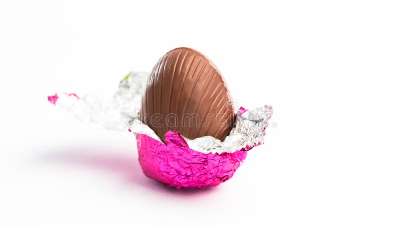 Easter egg unwrapped in pink foil on white background