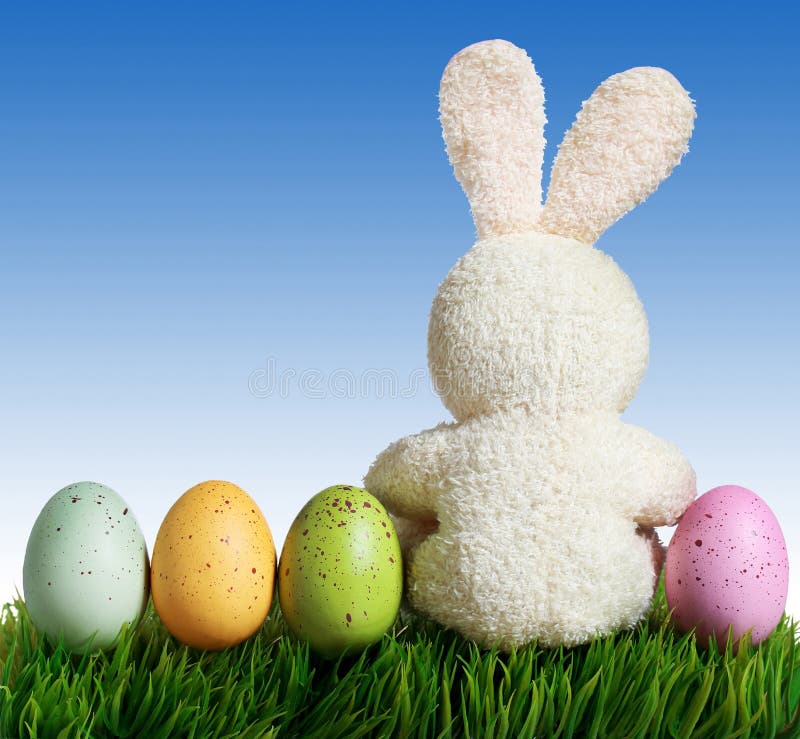 Easter eggs and rabbit on green grass with blue sky