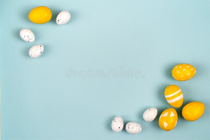 Easter eggs in yellow and white on a pastel blue background. Flat lay, top view