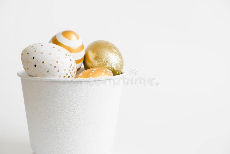 Easter golden decorated eggs in bucket on white background. Minimal easter concept. Happy Easter card with copy space for text