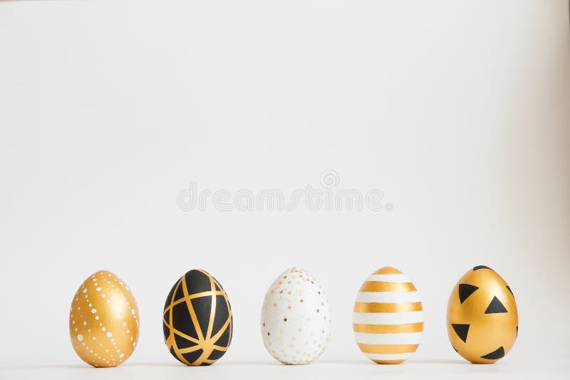 Easter golden decorated eggs stand in a row on white background. Minimal easter concept.