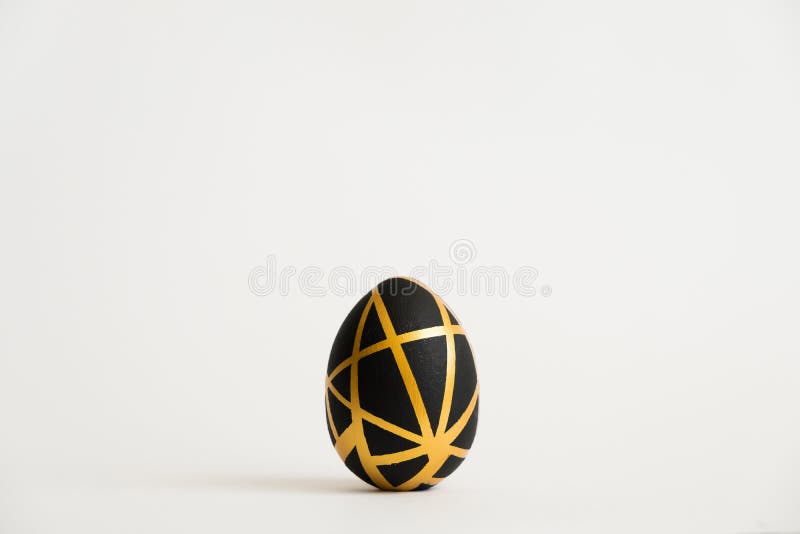 Easter golden egg with geometric black pattern isolated on white background. Minimal easter concept. Top view, flatlay