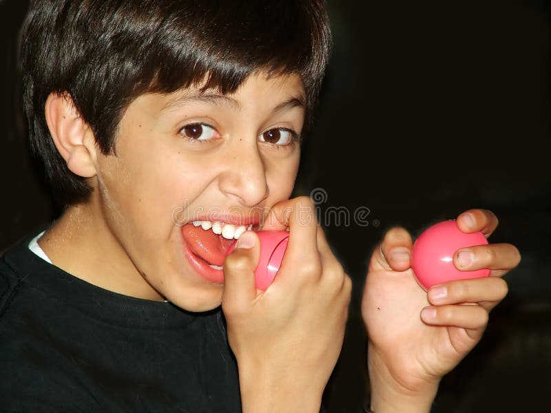 Young boy taking a bite of a plastic Easter egg. Young boy taking a bite of a plastic Easter egg