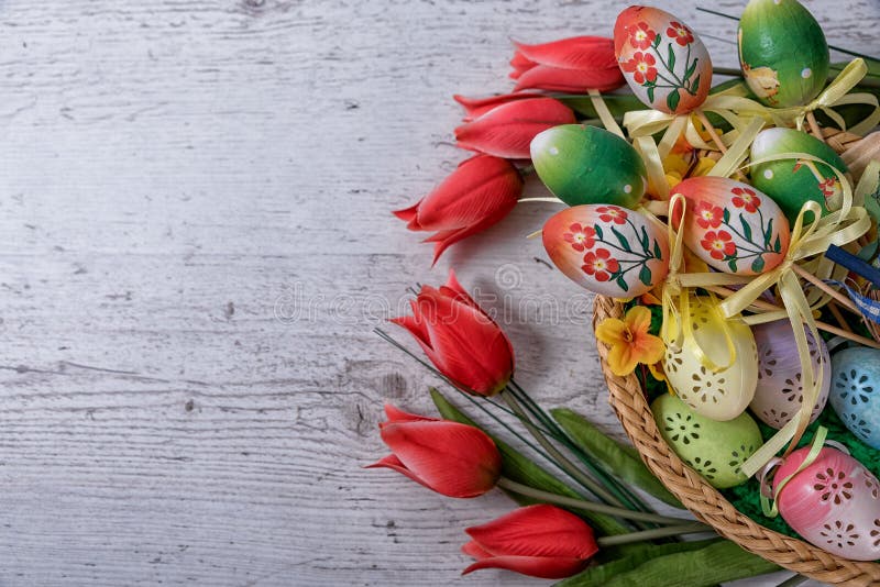 Easter, painted Easter eggs set in basket decoration red tulips, Easter decoration laid on a wooden table. Easter, painted Easter eggs set in basket decoration red tulips, Easter decoration laid on a wooden table