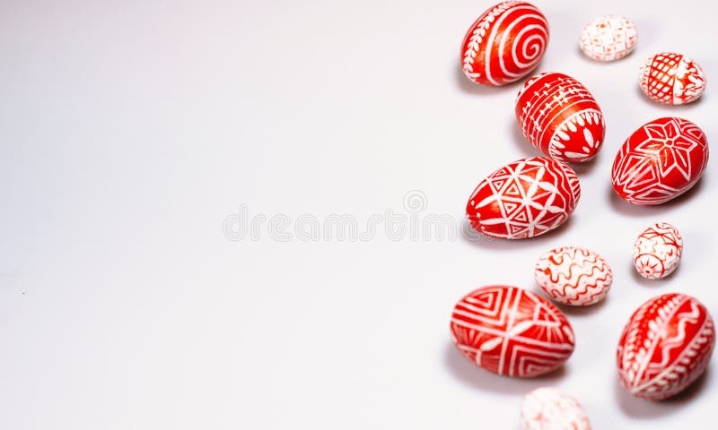 Easter red eggs with folk white pattern scattered white background from right side. Ukrainian traditional eggs pisanka and krashanka.