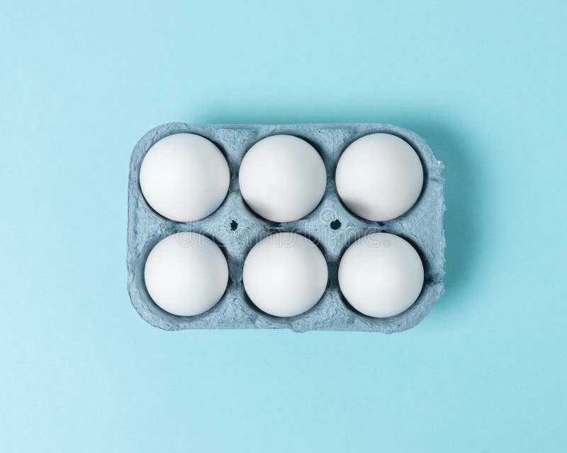 Easter White Eggs in Carton Tray on Blue Background. Flat Lay Stock
