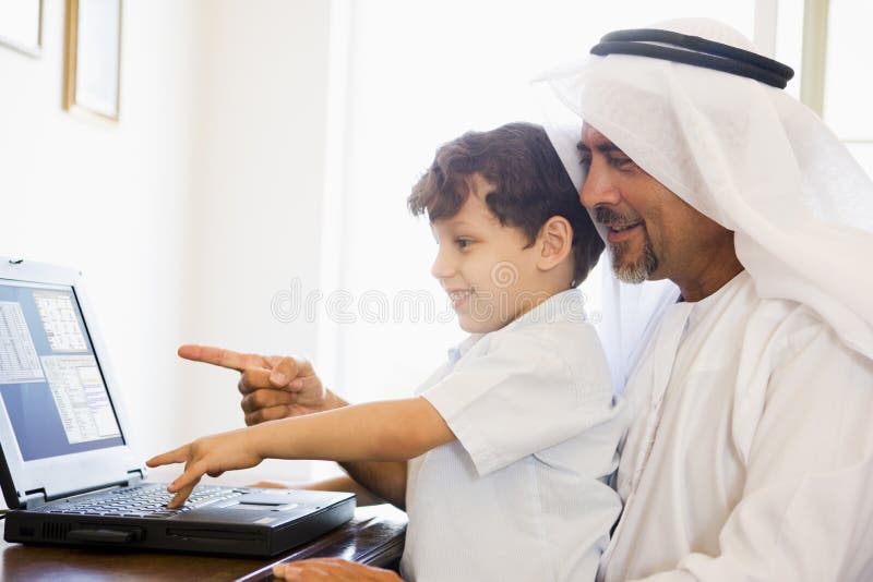 A Middle Eastern man and his son sitting in a home office. A Middle Eastern man and his son sitting in a home office