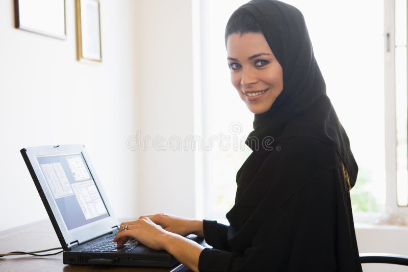 A Middle Eastern woman sitting in front of a computer at home. A Middle Eastern woman sitting in front of a computer at home