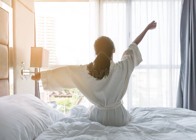 Easy lifestyle young Asian girl waking up in the morning taking a rest relaxing in hotel room for world lazy day