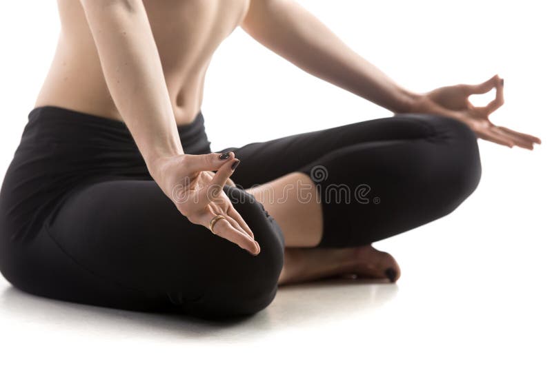 Sporty fit beautiful young woman in sportswear black pants working out, sitting in Sukhasana, Easy Posture, on meditation session, breathing, studio close-up, isolated, white background. Sporty fit beautiful young woman in sportswear black pants working out, sitting in Sukhasana, Easy Posture, on meditation session, breathing, studio close-up, isolated, white background