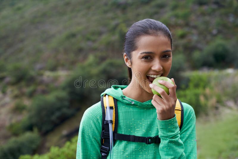 Eating, fruit and hiking portrait of woman in park, nature or apple in backpack for energy. Happy, trekking and hungry