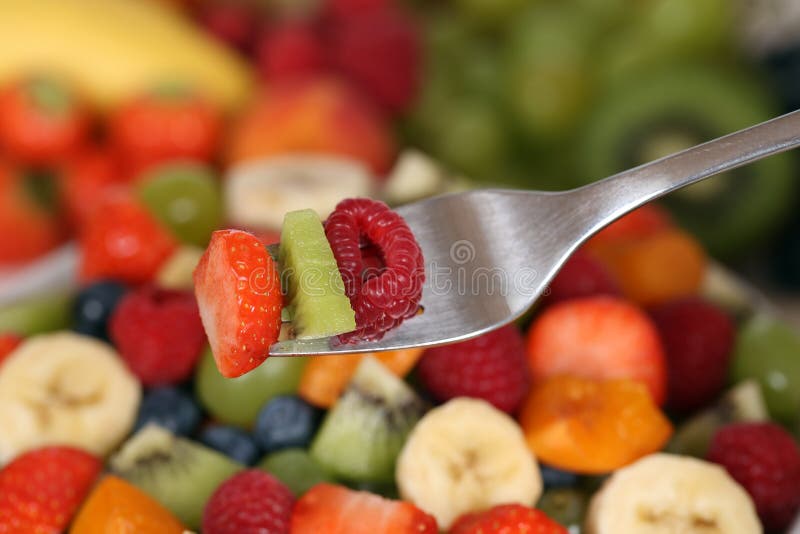 Eating fruit salad with fruits like strawberry, kiwi and raspberry on fork