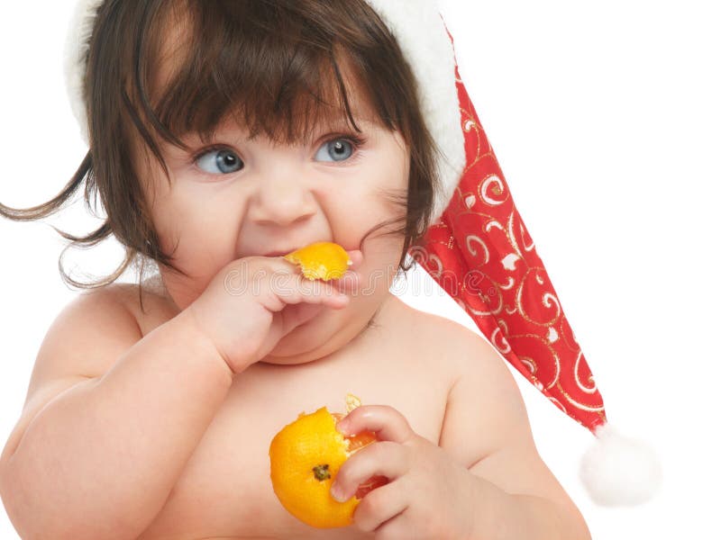 Cute baby in christmas hat eating orange