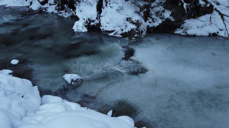Eau coulant sous la glace dans la forêt de montagne pendant un froid extrême en hiver clips vidéos