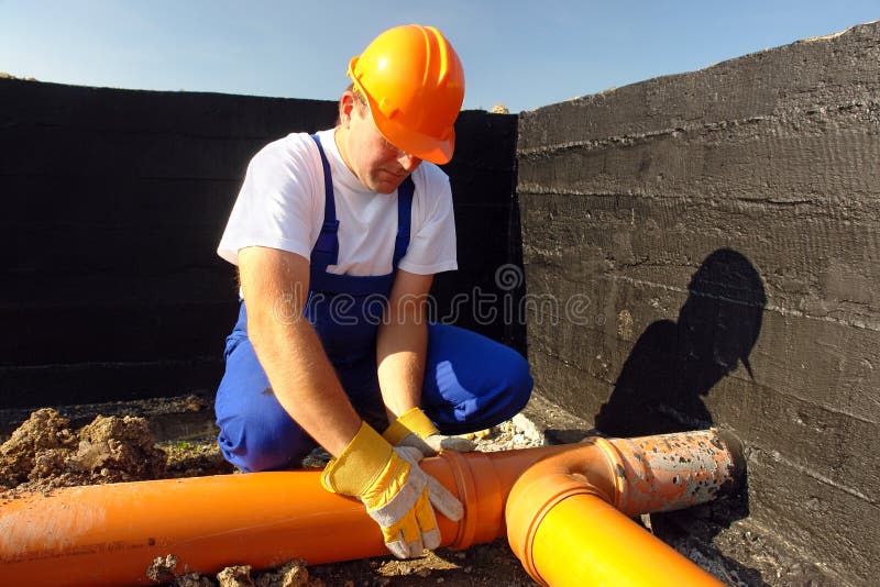 Plumber assembling pvc sewage pipes in house foundation. Plumber assembling pvc sewage pipes in house foundation