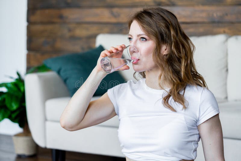 Eau potable de jeune femme blonde apr?s avoir fait des exercices s'?tendants de yoga ? la maison photos stock Eau potable de jeune femme blonde apr?s avoir fait des exercices s'?tendants de yoga ? la maison photos stock