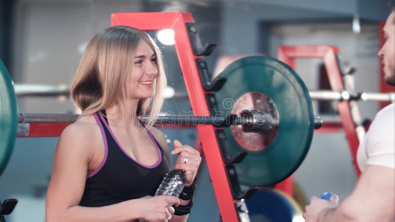 Eau potable parlante et de couples sportifs après des exercices dans le gymnase photographie stock Eau potable parlante et de couples sportifs après des exercices dans le gymnase photographie stock