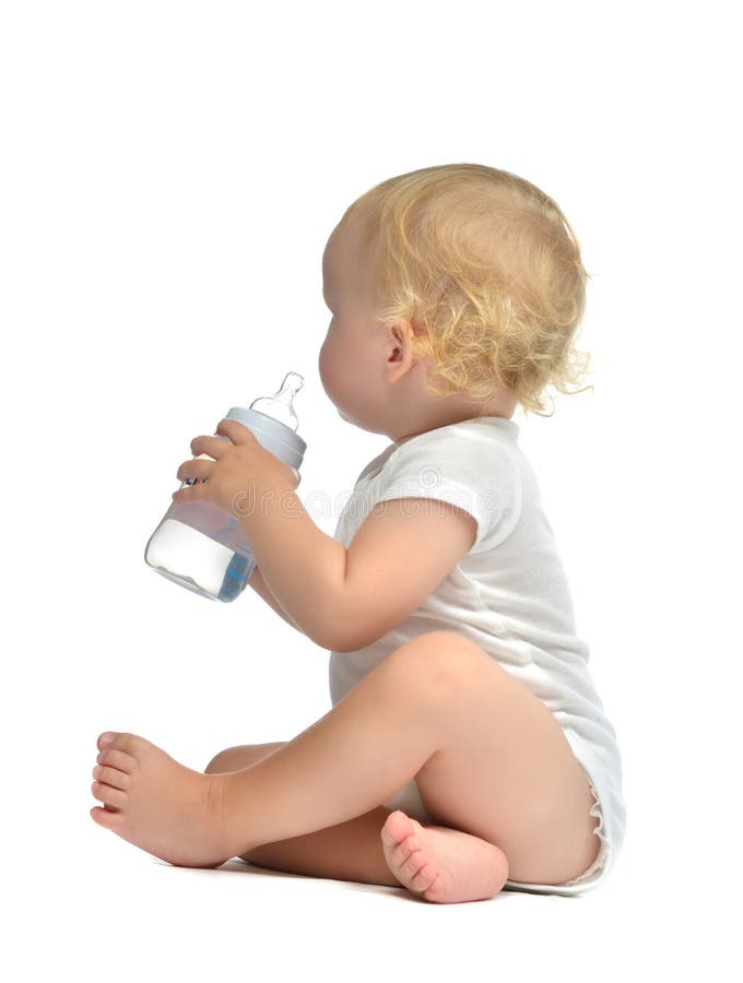 Infant child baby toddler sitting and drinking water from the feeding bottle on a white background. Infant child baby toddler sitting and drinking water from the feeding bottle on a white background