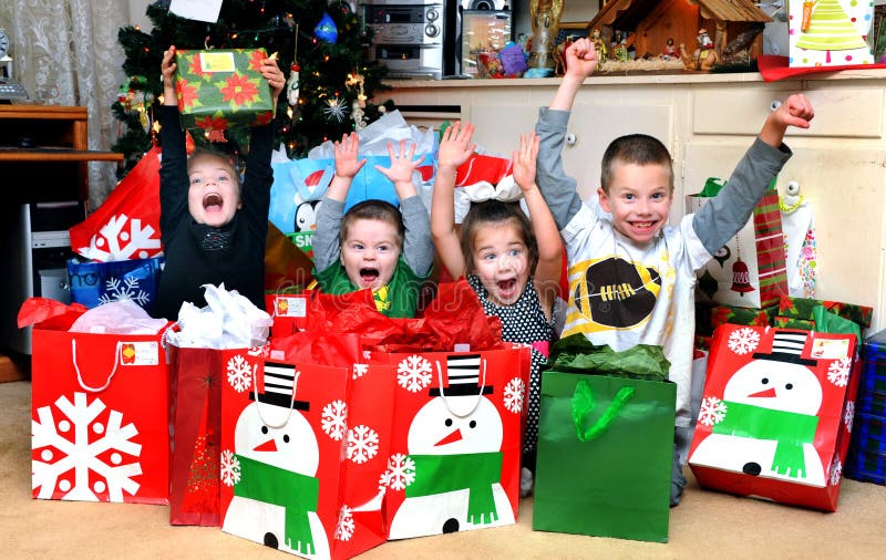Four children sit surrounded by Christmas packages. It is Christmas morning and their excitement is overflowing. There are two girls and two boys and they scream with joy. Four children sit surrounded by Christmas packages. It is Christmas morning and their excitement is overflowing. There are two girls and two boys and they scream with joy.