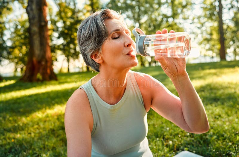 Echilibrul și sănătatea apei. doamna cu părul verde de vârstă înaintată care se simte sete în timpul antrenamentelor de dimineață stock image