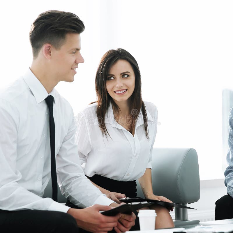 Echipă de afaceri care se uită la laptop în timp ce se așează la birou stock images