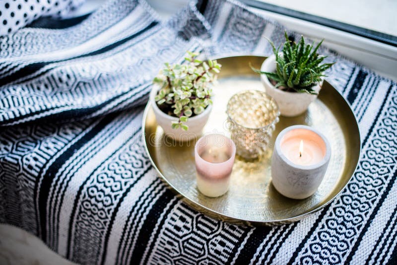 Echt flat binnenlands decor, aromatische kaarsen en installaties op uitstekend dienblad met hoofdkussens en deken op witte venste stock foto Echt flat binnenlands decor, aromatische kaarsen en installaties op uitstekend dienblad met hoofdkussens en deken op witte venste stock foto