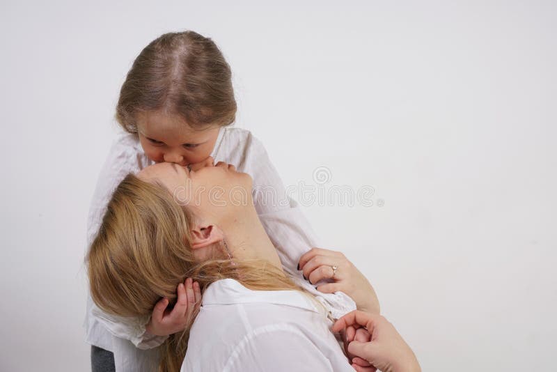 Echte familie van Kaukasische moeder en dochter in witte overhemden op de studioachtergrond royalty-vrije stock fotografie Echte familie van Kaukasische moeder en dochter in witte overhemden op de studioachtergrond royalty-vrije stock fotografie
