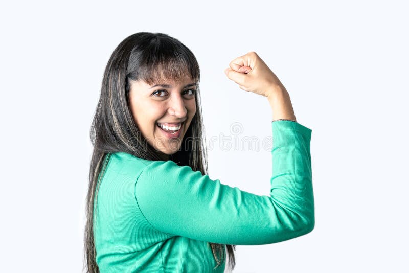 Real Latin woman showing her biceps over white background while looking at camera. Women's rights and empowerment concept. Copy space over isolated background. Real Latin woman showing her biceps over white background while looking at camera. Women's rights and empowerment concept. Copy space over isolated background