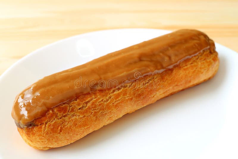 Eclair délicieux de caramel servi du plat blanc, du foyer sélectif et du fond brouillé image libre de droits Eclair délicieux de caramel servi du plat blanc, du foyer sélectif et du fond brouillé image libre de droits