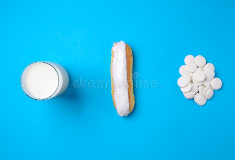 Eclair saporito con i chip della cioccolata bianca e bicchiere di latte sul fondo di colore fotografie stock libere da diritti Eclair saporito con i chip della cioccolata bianca e bicchiere di latte sul fondo di colore fotografie stock libere da diritti