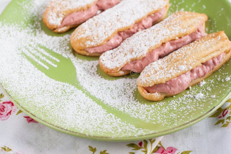 Eclairs z śmietanką truskawek malinki i sproszkowany cukier zdjęcia royalty free Eclairs z śmietanką truskawek malinki i sproszkowany cukier zdjęcia royalty free