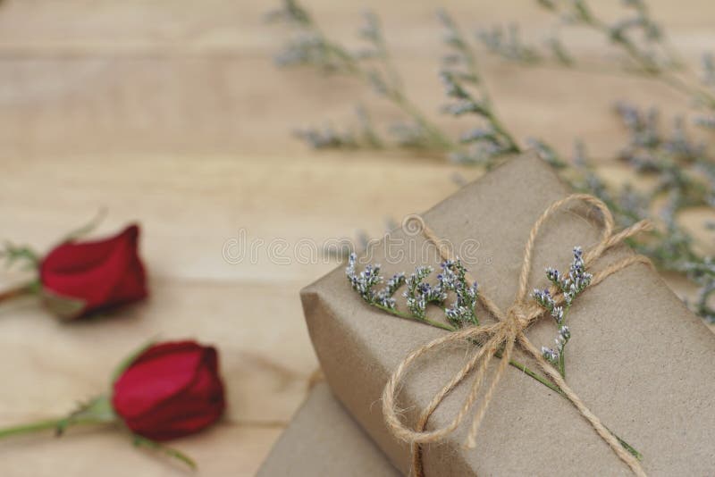 Eco friendly brown paper wrapped gift box present decorated with rose and other flowers on wooden background, valentine ornamental stock photos Eco friendly brown paper wrapped gift box present decorated with rose and other flowers on wooden background, valentine ornamental stock photos