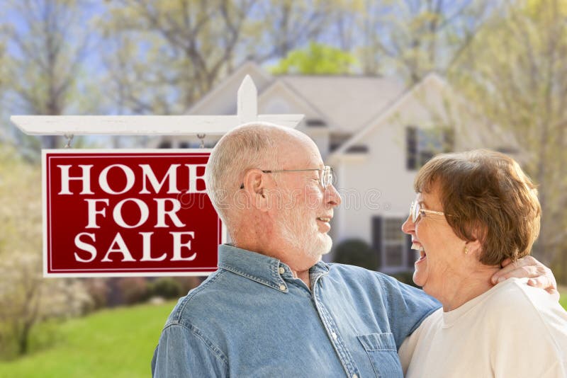 Happy Senior Couple Front of For Sale Real Estate Sign and House. Happy Senior Couple Front of For Sale Real Estate Sign and House.