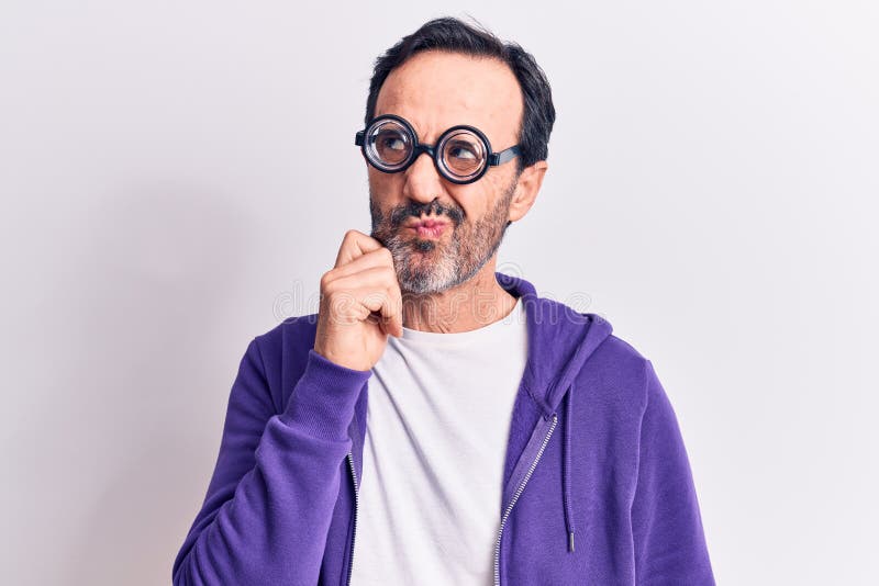La edad media guapo freaky hombre usando lentes mudos sobre fondo blanco aislado pensando concentrado sobre duda con el dedo en la barbilla y mirando hacia arriba preguntándose