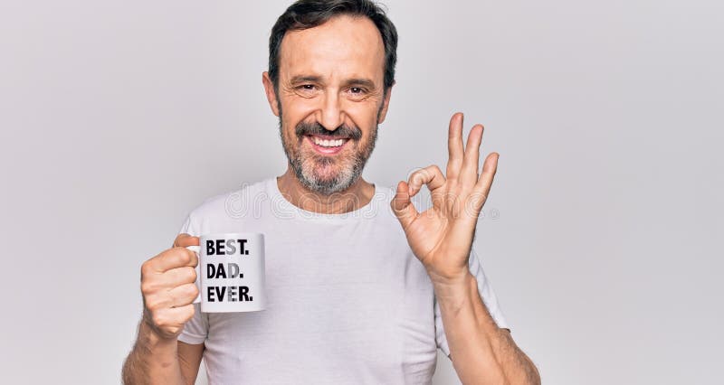 Edad media hombre guapo beber taza de café con mejor papá nunca mensaje haciendo ok signo con los dedos sonriendo gesto amistoso foto de archivo