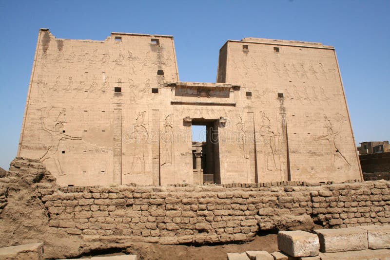 The Temple of Edfu is an ancient Egyptian temple located on the west bank of the Nile in the city of Edfu. It is the second largest temple in Egypt after Karnak and one of the best preserved. The temple, dedicated to the falcon god Horus, was built in the Ptolemaic period between 237 and 57 BCE. The inscriptions on its walls provide important information on language, myth and religion during the Greco-Roman period in ancient Egypt. They are translated by the german Edfu-Project. Edfu was one of several temples built during the Ptolemaic period, including Dendera, Esna, Kom Ombo and Philae. Its size reflects the relative prosperity of the time. Construction began in 237 BCE during the reign of Ptolemy III and completed in 57 BCE under Ptolemy XII. It was built on the site of an earlier, smaller temple also dedicated to Horus, although the previous structure was oriented east-west rather than north-south as in the present site. A ruined pylon lies just to the east of the current temple; inscriptional evidence has been found indicating a building program under New Kingdom rulers Ramesses I, Seti I and Ramesses II. The temple of Edfu fell into disuse as a religious monument following Theodosius I's edict banning non-Christian worship within the Roman Empire in 391 CE. As elsewhere, many of the temple's carved reliefs were razed by followers of the Christian faith which came to dominate Egypt. This photograph is part of the Imagine Collection, hosted by Alamy. The Temple of Edfu is an ancient Egyptian temple located on the west bank of the Nile in the city of Edfu. It is the second largest temple in Egypt after Karnak and one of the best preserved. The temple, dedicated to the falcon god Horus, was built in the Ptolemaic period between 237 and 57 BCE. The inscriptions on its walls provide important information on language, myth and religion during the Greco-Roman period in ancient Egypt. They are translated by the german Edfu-Project. Edfu was one of several temples built during the Ptolemaic period, including Dendera, Esna, Kom Ombo and Philae. Its size reflects the relative prosperity of the time. Construction began in 237 BCE during the reign of Ptolemy III and completed in 57 BCE under Ptolemy XII. It was built on the site of an earlier, smaller temple also dedicated to Horus, although the previous structure was oriented east-west rather than north-south as in the present site. A ruined pylon lies just to the east of the current temple; inscriptional evidence has been found indicating a building program under New Kingdom rulers Ramesses I, Seti I and Ramesses II. The temple of Edfu fell into disuse as a religious monument following Theodosius I's edict banning non-Christian worship within the Roman Empire in 391 CE. As elsewhere, many of the temple's carved reliefs were razed by followers of the Christian faith which came to dominate Egypt. This photograph is part of the Imagine Collection, hosted by Alamy.