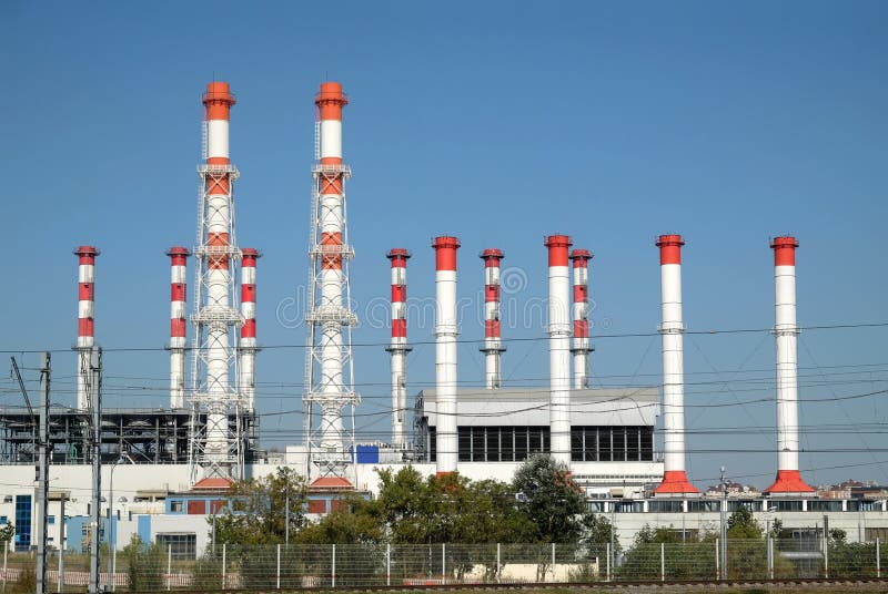 Edificio de la central eléctrica con muchos altos tubos industriales rojos y blancos sobre el cielo azul despejado claro en vista foto de archivo libre de regalías Edificio de la central eléctrica con muchos altos tubos industriales rojos y blancos sobre el cielo azul despejado claro en vista foto de archivo libre de regalías