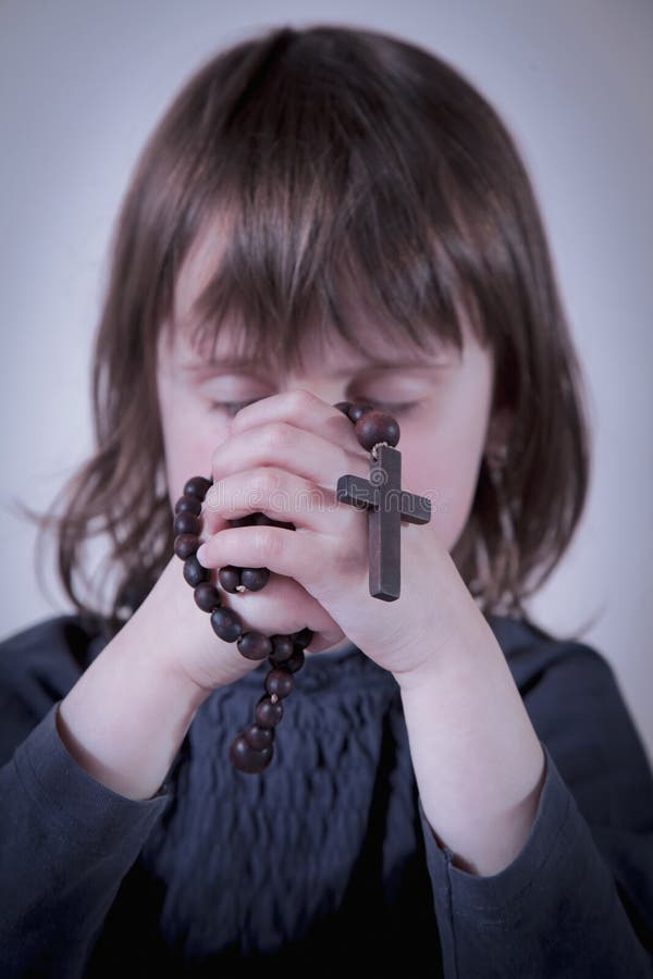 Educación de la educación religiosa del niño Poco muchacha linda que ruega y que sostiene un rosario imagen de archivo Educación de la educación religiosa del niño Poco muchacha linda que ruega y que sostiene un rosario imagen de archivo