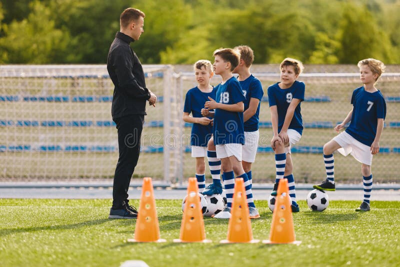 Educación en fútbol para niños. clase de educación física para niños en edad escolar, entrenadores jóvenes con hijos fotos de archivo libres de regalías