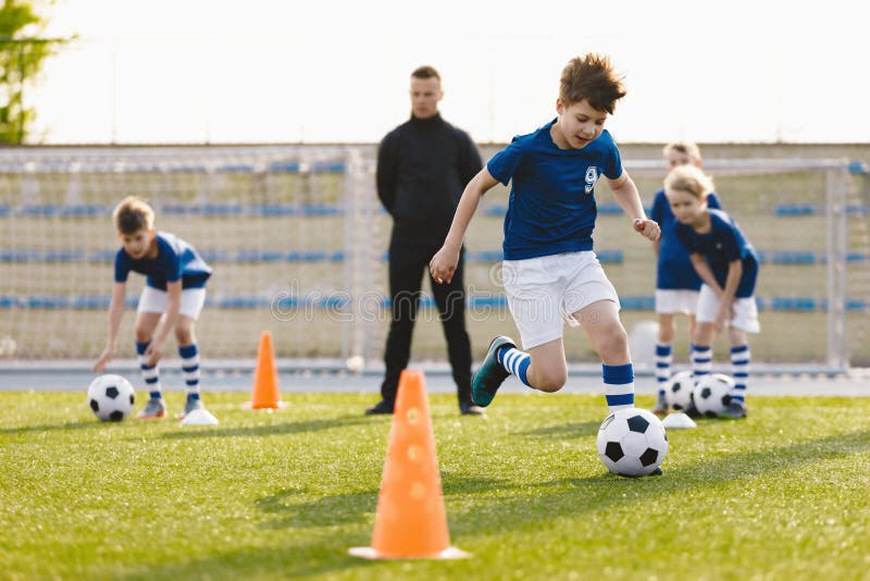 Educación en fútbol para niños. clase de educación física para escolares. entrenador joven con niños imagenes de archivo