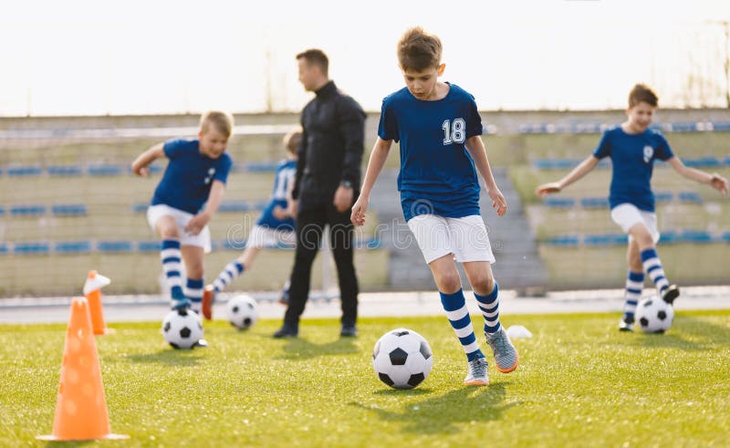 Educación en fútbol para niños. clase de educación física para escolares. entrenador joven con niños foto de archivo libre de regalías