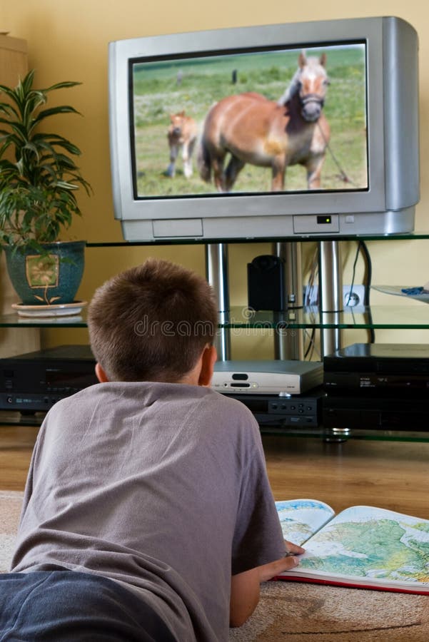 Educational TV - teenage boy reading a map while watching nature TV programme. Atlas book stock images, royalty-free photos and pictures