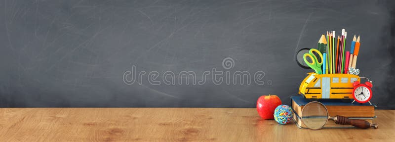 Education and back to school concept. pencils stand as bus over wooden desk infront of classroom blackboard