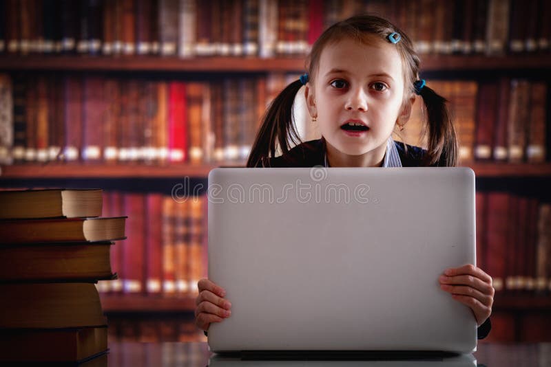 Education concept. Young beautiful child girl working  with laptop and reading books in library. Horizontal image. Copy space