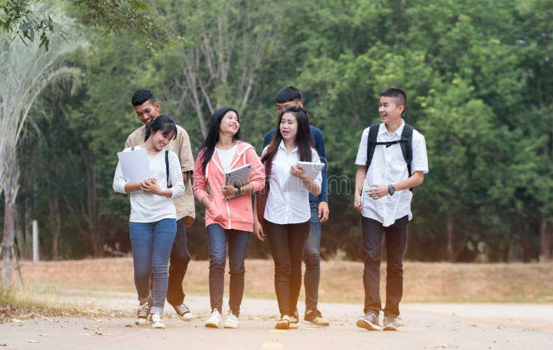 Education learning Concept: Confident Asian Students groups walking hold books, tablet notebook at Outside classroom in university