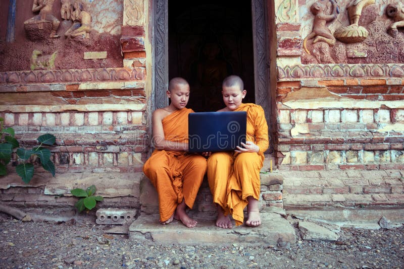 Education of Novice monk Buddhism using laptop learning with friends sitting in the buddhist church at Nong Khai Thailand.